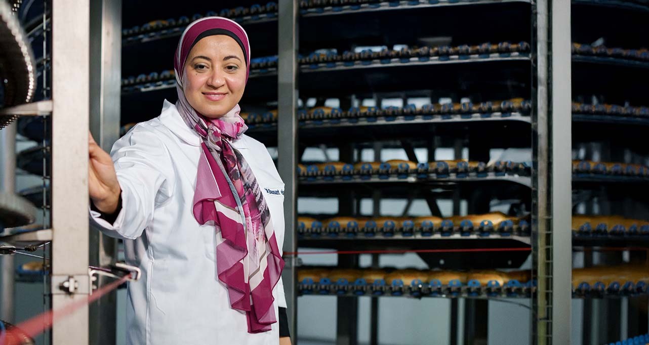 Woman looking at the camera standing in front of a factory machine